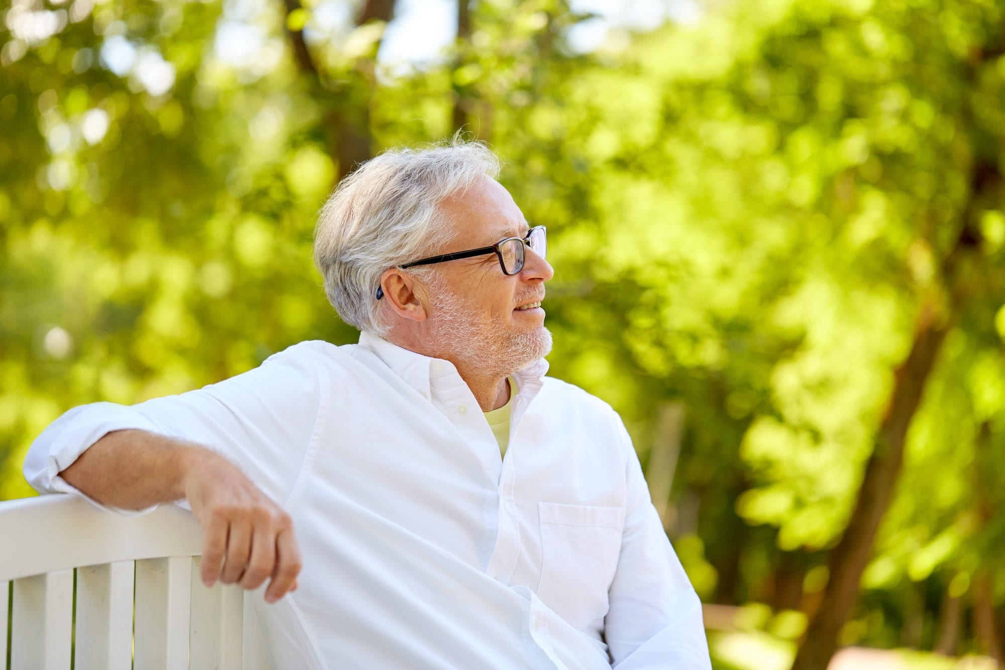 happy senior man in glasses sitting at summer park